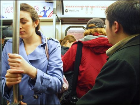 Woman holding bar in subway car looking nauseous