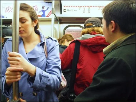 Woman holding bar in subway car looking nauseous