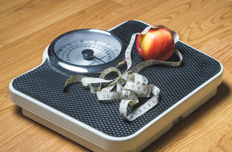 Weight loss - a scale with an apple and measuring tape on top